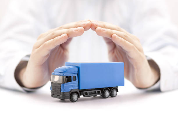 Car insurance. Blue truck miniature covered by hands